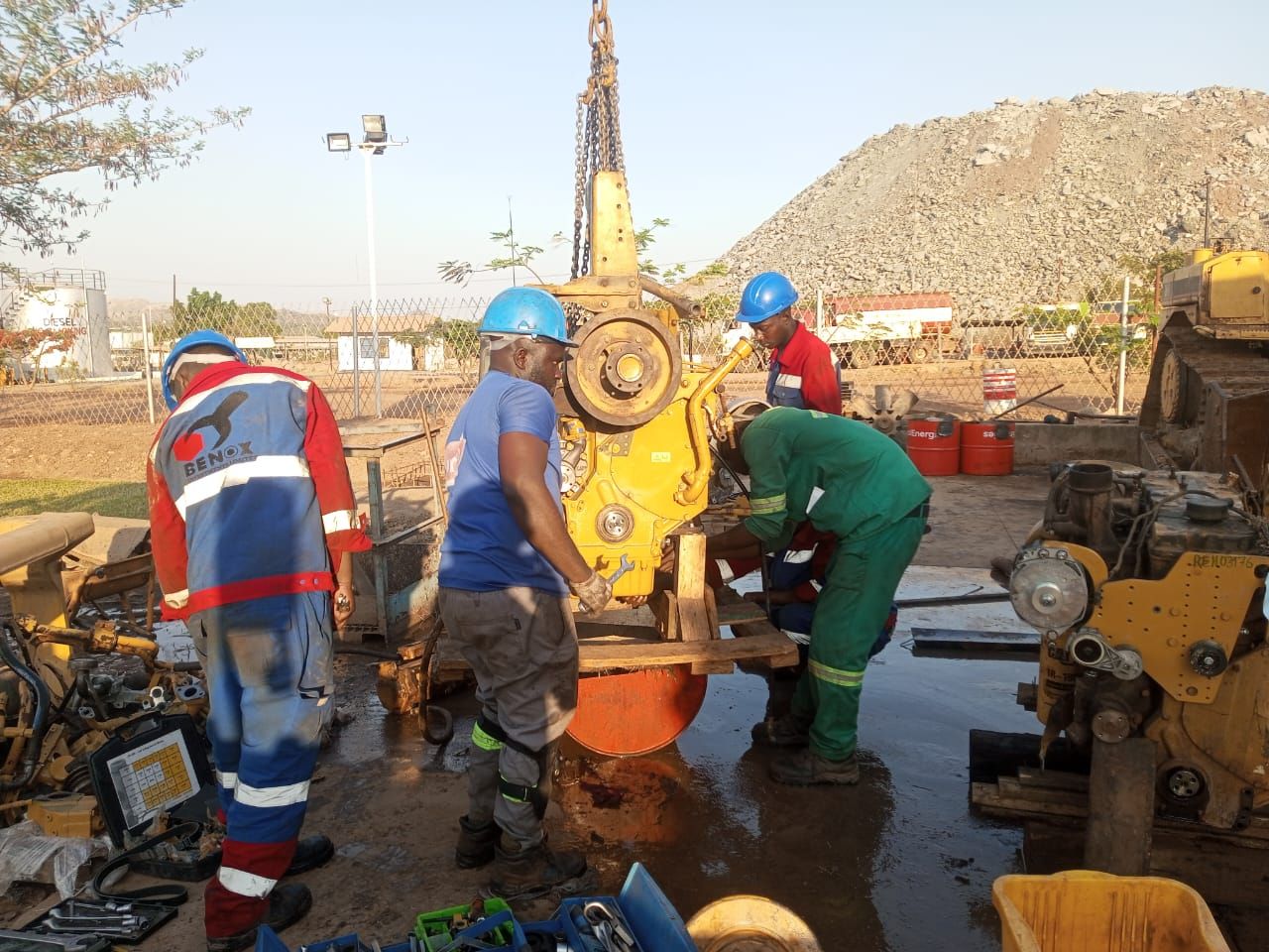 Team lowering an engine on a chain hoist onto a work stand